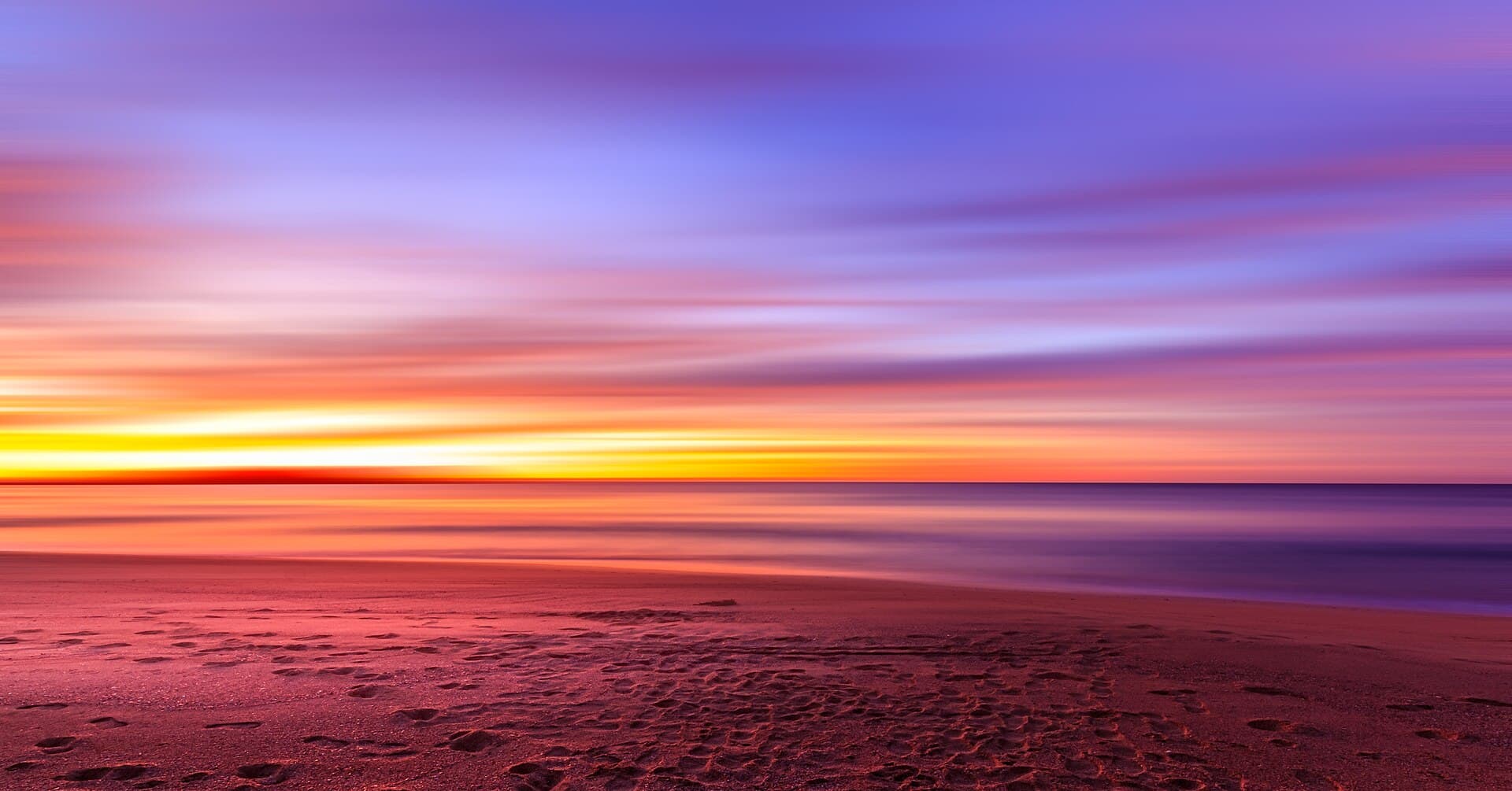 Long-exposure dusk over a New South Wales beach, the water a deep violet and the horizon almost gone.