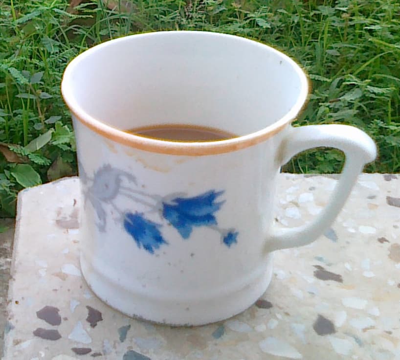 A plain cup of tea on a wooden table in soft light, the sort of still object that fills the minutes before a conversation starts.