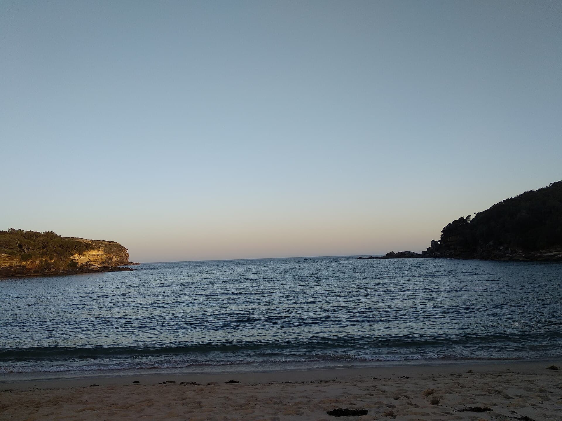The lagoon and sandstone at Wattamolla in Royal National Park, a wide open place a family might walk while a conversation happens sideways.